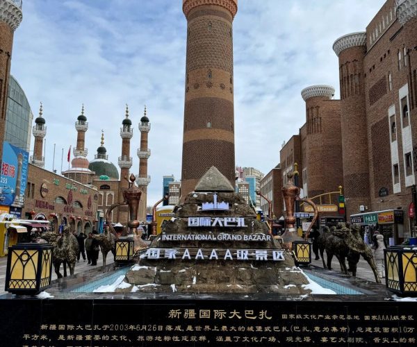 Grand Bazaar,Urumqi,Chinatrip Tall brick minaret towers flank a bazaar complex at the International Grand Bazaar, with a tiered fountain and signs in English and Chinese in the foreground.