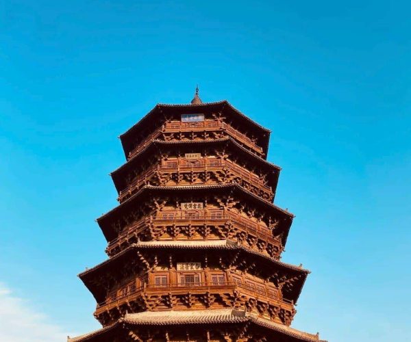 Datong,Shanxi,Chinatravel Seven-story traditional Chinese pagoda with ornate wooden eaves sits against a bright blue sky, with visitors at the base.