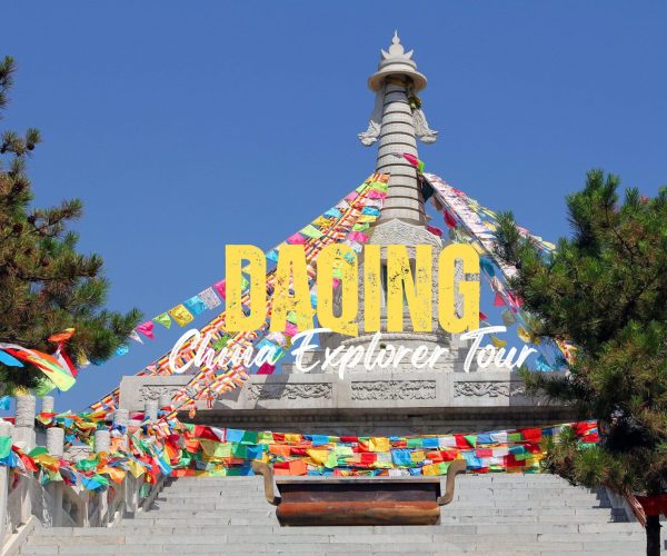 Daqing,Heilongjiang,Chinatravel Promotional travel image of a Buddhist stupa with multicolored prayer flags against a blue sky, bordered by stairs and trees.