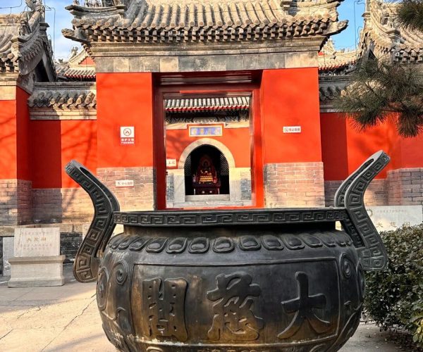 Daci Pavilion,Baoding,China tour Large bronze ceremonial cauldron with dragon-shaped handles in the foreground, set before a red Chinese temple gate with ornate tiled roofs.