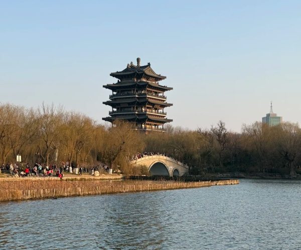 Daming Lake,Jinan,China tour Six‑story Chinese pagoda beside a lake, with a stone arch bridge and visitors along the shore.