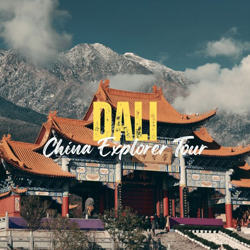 Dali,Yunan,Chinatravel Traditional Chinese temple with orange tiled roofs set against snow-capped mountains, overlaid with bold 'DALI' and cursive 'China Explorer Tour' text.