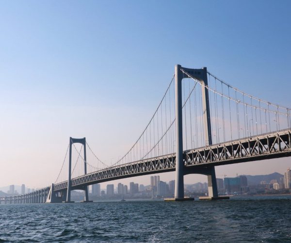 Dalian Weathe,Dalian,Chinatravel Suspension bridge spanning a wide body of water with tall towers and a city skyline in the distance.