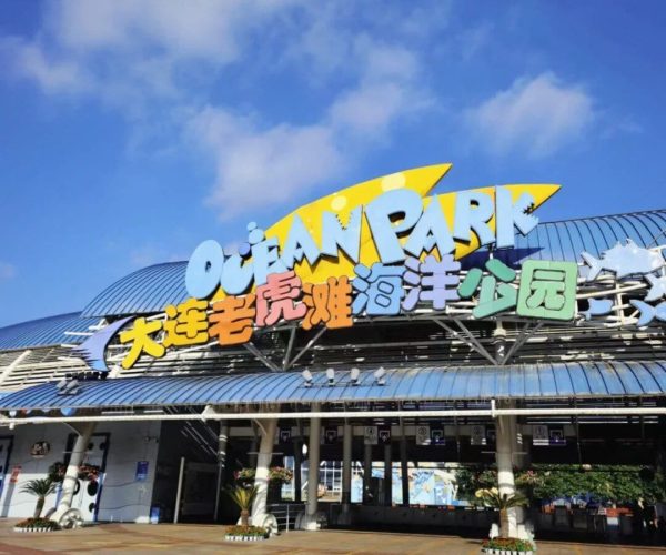 Tiger Beach Ocean Park,Dalian,Chinatravel Entrance to Ocean Park with a large colorful sign and Chinese characters, under a clear blue sky.