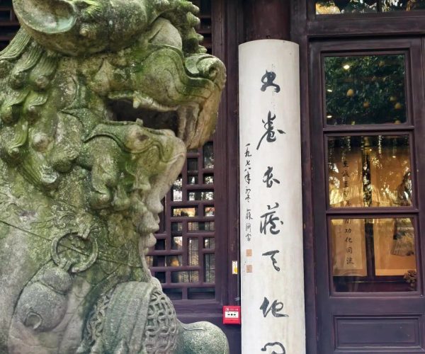 Tianyi Pavilion,Ningbo,Chinatravel Mossy stone guardian lion statue beside a tall white scroll with Chinese calligraphy on a dark wooden doorway.