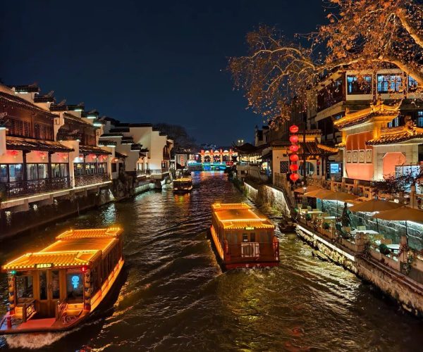 Confucius Temple & Qinhuai Rive,Nanjing,China tour Night view of a canal in a traditional Chinese town, with lit boats on the water and red lanterns along the banks at dusk.