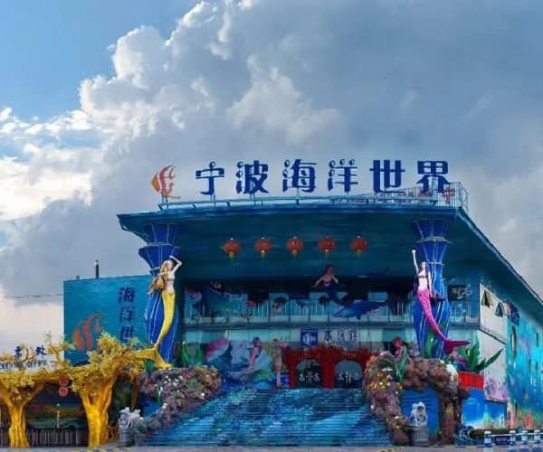 Ningbo Ocean World,Ningbo,Chinatravel Front of Ningbo Ocean World with blue building, mermaid statues, red lanterns, and decorative rock arches at the entrance for visitors
