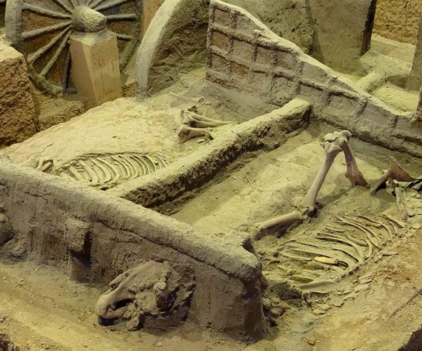 Yin Ruins ,Anyang,Chinatravel Recreated ancient grave in a dusty tomb with skeletal remains, a wooden wheel, and stone walls nearby