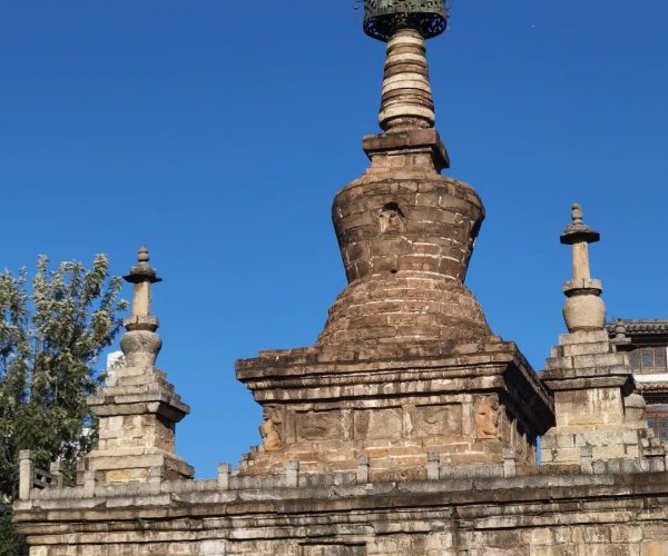 Kunming Ancient Town ,Kunming,Chinatravel Stone arched gateway made of weathered bricks, topped by a multi-tiered stupa and ornate spire against a clear blue sky