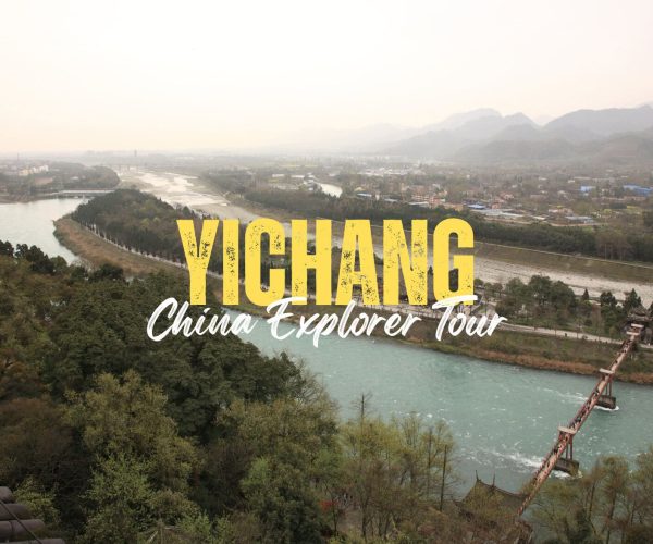 Yichang,Hunan,Chinatravel Aerial view of Yichang landscape with a river and distant mountains; large yellow 'YICHANG' and white 'China Explorer Tour' text overlay on the scene.