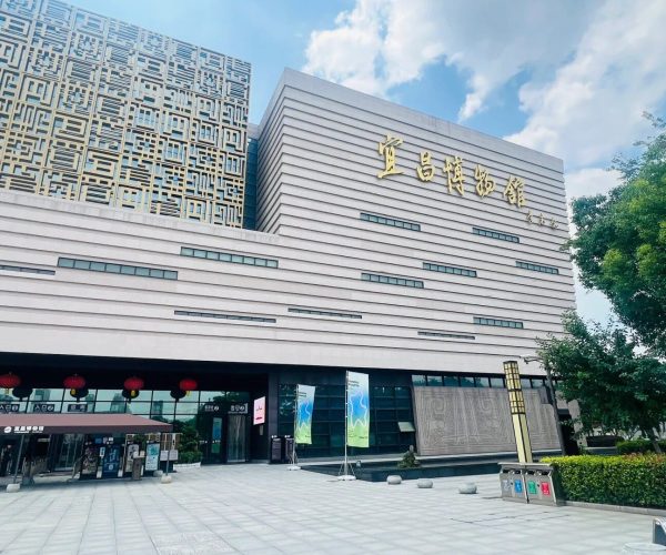 Yichang Museum,Yichang,Chinatravel Exterior view of a modern museum with horizontal beige façade, gold Chinese characters on the wall, and red lanterns at the entrance.