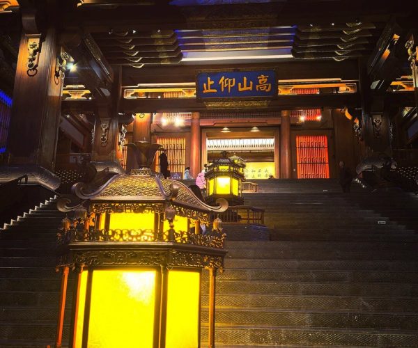 Nishan Sacredland,Qufu,China tour Ornate Asian temple interior with a grand stairway, glowing yellow lanterns, and intricate woodwork above the steps.