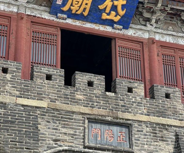 Mount Tai Temple ,Tai'an,China tour Historic Chinese gate with a blue plaque featuring gold characters, red lattice windows, and crenellated gray brick walls beneath a decorative roof. The sign at the bottom reads 正阳门 (Zhengyang Gate).