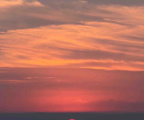 Yueyang,Hunan,Chinatour A vibrant sunset over the water with colorful sky and a small boat in the distance.