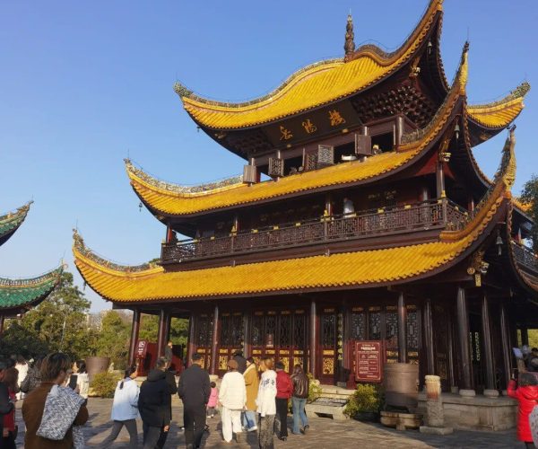 Yueyang Tower,Yueyang,Chinatravel Three-story Chinese temple with yellow tiled roofs and dark wooden doors, visitors walking toward the entrance on a sunny day.