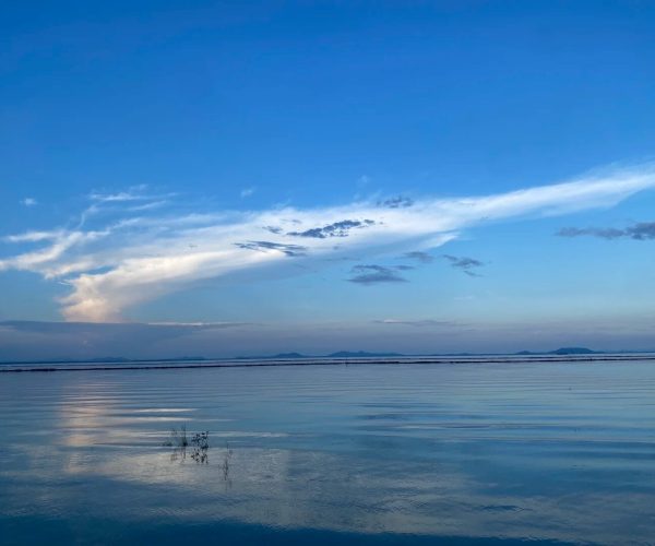 Chaohu Lake Scenic Area,Hefei,China tour Calm lake scene with a blue sky, a long white cloud across the horizon, and reflections on the water's surface.