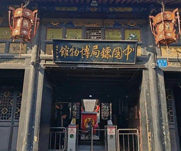 Pingyao Museum & Cultural Shows,Pingyao,Chinatravel Entrance to a traditional Chinese museum with a gold-inscribed sign, ornate lanterns, and visitors entering through a gated archway.