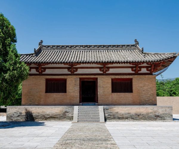 Guangrenwang Temple,Yuncheng,Chinatravel Traditional Chinese brick hall with a gray tiled roof, red wooden supports, and a central doorway framed by two windows in a paved courtyard