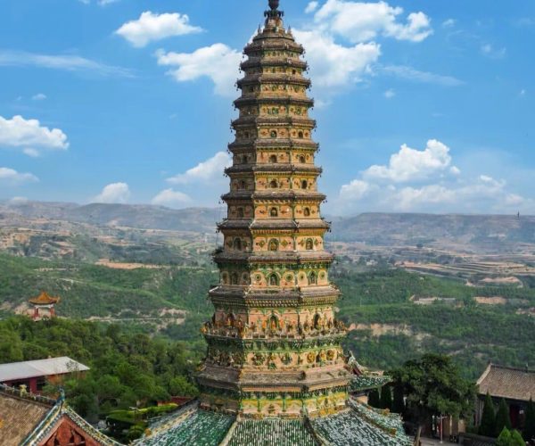 Guangsheng Temple,Linfen,Chinatravel Tall multi-tiered pagoda with ornate carvings in a temple complex, overlooking green hills and a blue sky.]