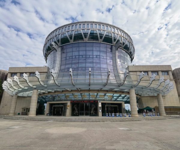Guangxi Museum of Nationalities,Nanning,Chinatravel Front view of a futuristic circular glass museum with a curved skylight and metal supports over the entrance.