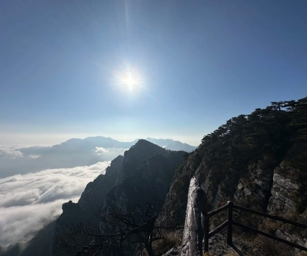 Mount Lushan (Lushan Scenic Area),Jiujiang,China tour Sun over a jagged mountain ridge with a sea of clouds below and a railing-lined cliff path in the foreground.