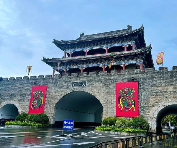 Kaifeng Ancient City Wall,Kaifeng,Chinatravel Stone fortress gate with an arched entrance and a ornate, multi-tier Chinese pagoda above; red banners flank the arch.