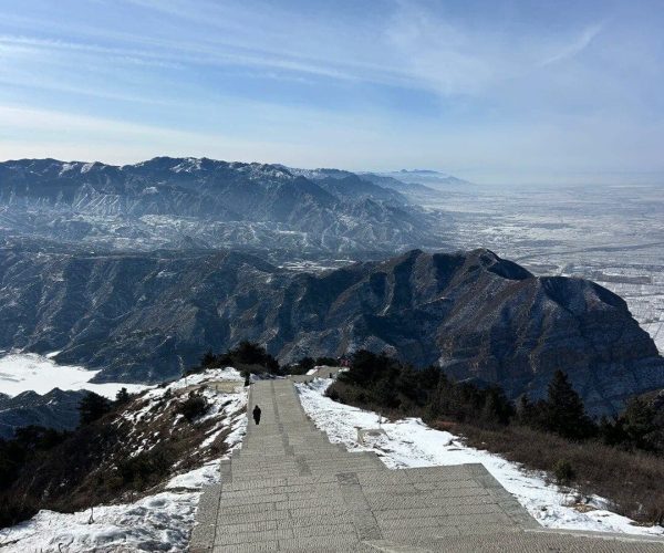 Mount Heng ,Datong,Chinatravel Stone stairway descends a snowy mountainside toward a distant valley and blue sky above.