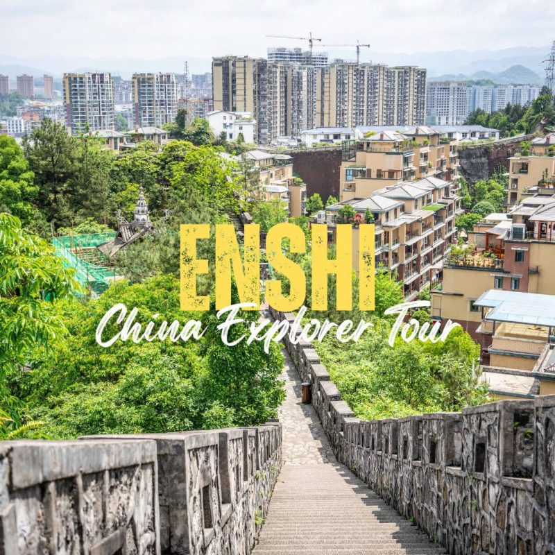 Enshi,Hubei,Chinatravel Promotional banner for ENSH China Explorer Tour with a stone staircase leading to a cityscape of buildings and greenery.