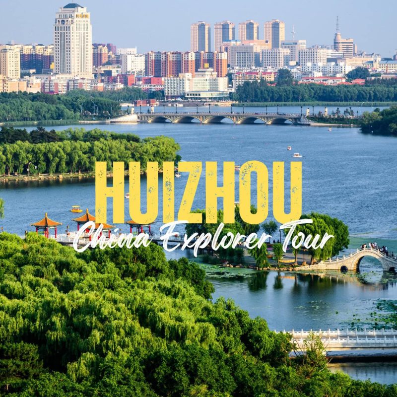 Huizhou,Guangdong,Chinatravel Hangzhou skyline over a lake with a curved stone bridge and lush green trees in the foreground; bold yellow 'HANGZHOU' and white script text 'China Explorer Tour' overlaid.