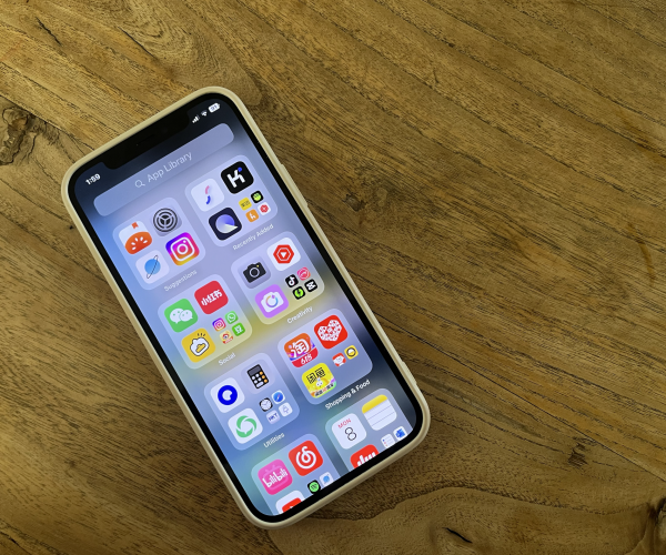 How To Stay Connected In China 2025: Internet, VPN And SIM Cards, chinaexplorertour, Smartphone with a grid of colorful app icons on a wooden table surface, seen at an angle.