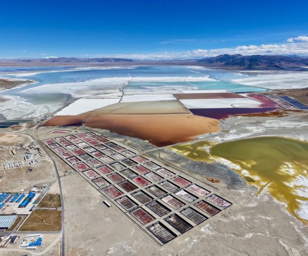 Zhabuyekacha Salt Lake,Shigatse,China tour Aerial view of colorful salt evaporation ponds in a desert landscape, with a grid of rectangular basins and distant mountains.