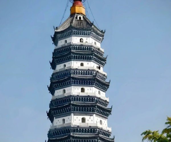 Zhenfeng Pagoda,Anqing,China tour White multi-tiered Chinese pagoda with dark blue eaves and a red-orange spire against a clear blue sky, part of a temple complex
