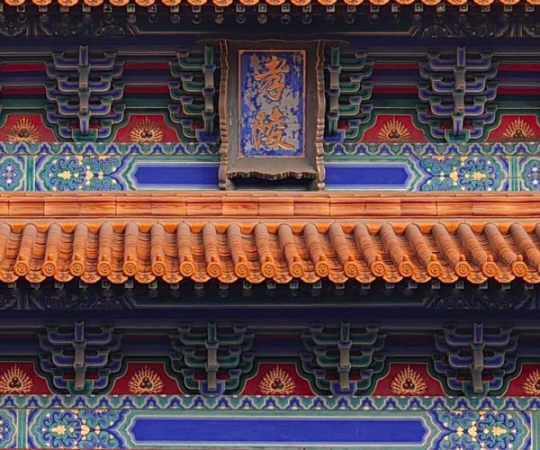 Ming Xiaoling Tomb,Nanjing,China tour Ornate traditional Chinese temple roof with colorful wooden brackets and a blue plaque in the center.