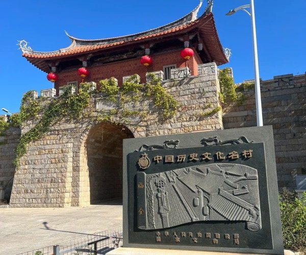 Jinjiang Ancient City,Quanzhou,Chinatravel Historic Chinese fortress gate with a curved roof, red lanterns, and ivy-covered stone walls against a bright blue sky, an architectural landmark. Reflects traditional design and entry point to a historic site.