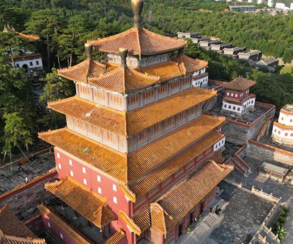 Puning Temple,Chengde,China tour A multi-tiered orange-tiled pagoda in a red-walled temple complex set among trees and green hills. (Aerial view)