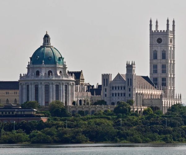 Songshan Lake,Dongguan,Chinatravel A historic university campus by the river featuring a green copper-domed central building and a tall clock tower.