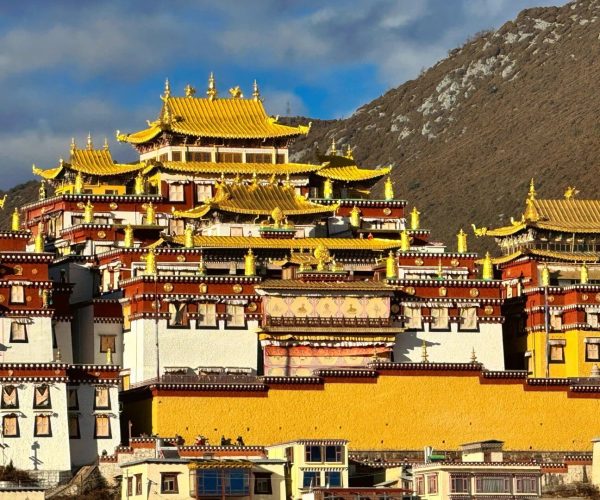 Songzanlin Monastery,Shangri-La,Chinatravel Golden-roofed Tibetan monastery perched on a hillside with colorful layered walls against a blue sky.