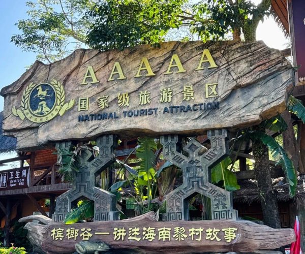 Betel Nut Valley – Li & Miao Cultural Heritage Park,Sanya,Chinatravel Large rock sign reading 'National Tourist Attraction' with a crest, at an outdoor entrance.