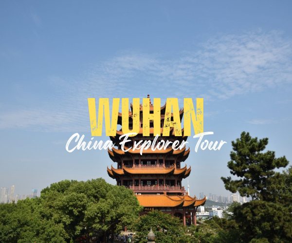 Wuhan,Hubei,Chinatravel Text overlay reading 'VUHAN China Explorer Tour' over a traditional Chinese pagoda with trees and a city skyline behind it.