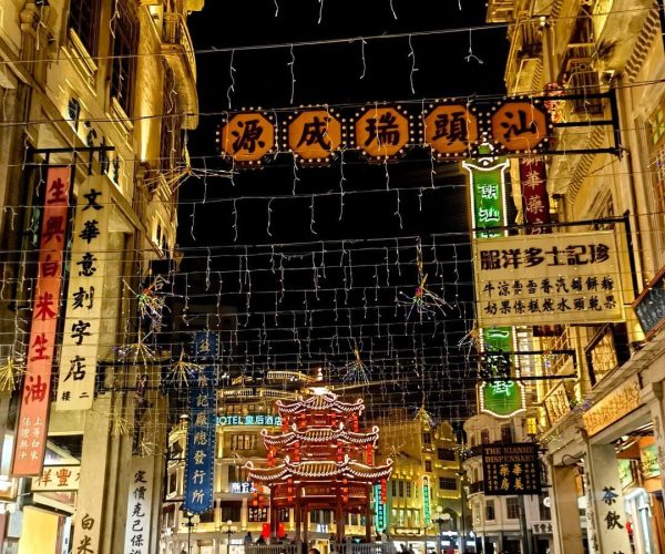 Little Park Historic District,Shantou,Chinatravel Nighttime Chinatown street with string lights, colorful vertical signs, and a lit red pagoda at the end; pedestrians walk along the stone-paved road.