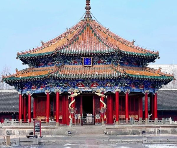 Shenyang Imperial Palace,Shenyang,China tour Front view of a traditional Chinese temple with a multi-tiered, orange-green tiled roof and bright red columns in a courtyard setting.