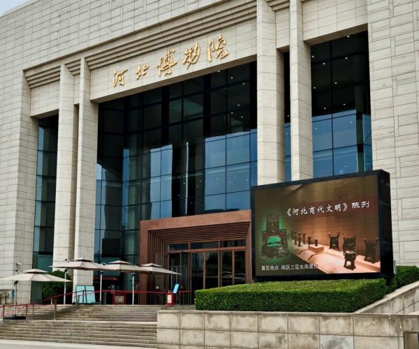 Hebei Provincial Museum,Shijiazhuang,China tour Exterior of a large beige stone building with glass windows and gold Chinese signage above the entrance.