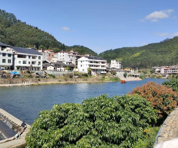 Quanzhou Weather,Fujian,Chinatravel Riverside town with white apartment buildings along a calm river, backed by green hills under a clear blue sky