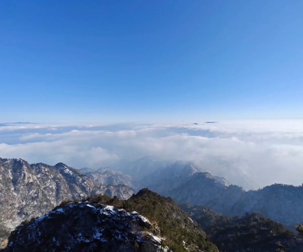 Baiyun Mountain & Scenic Area,Luoyang,Chinatravel Snow-dusted rocky mountain ridge rises above a sea of clouds under a clear blue sky.
