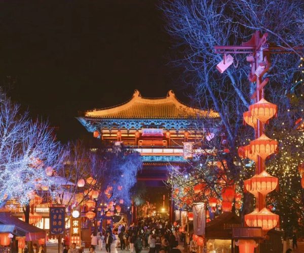 Millennium City Park,Kaifeng,Chinatravel Nighttime street festival with red lanterns and string lights leading to a traditional Chinese gate/pavilion.