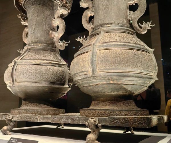 Hubei Provincial Museum,Wuhan,Chinatravel Two enormous ancient bronze ritual vases with dragon-handled rims on a raised museum display platform, indoors