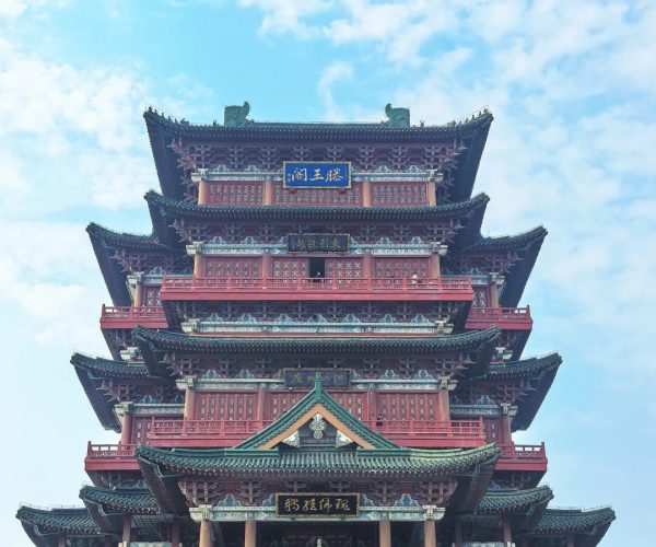 Tengwang Pavilion,Nanchang,China tour Five-tier red-and-green Chinese pagoda-style temple with ornate eaves, set against a blue sky; visitors on the steps.