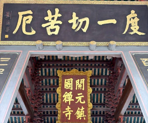Kaiyuan Temple,Chaozhou,Chinatravel Temple entrance interior with a large black signboard in gold Chinese characters and ornate red-gold plaques, beneath a teal and gold ceiling.