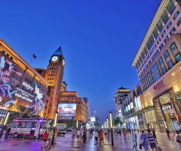 Wuangfujing, Beijing, chinatravel, Pedestrian street at dusk with illuminated storefronts and a tall clock tower against a deep blue sky.)