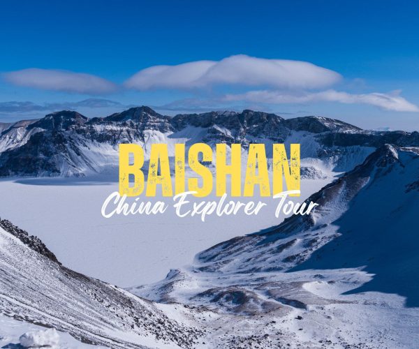 Baishan,Jilin Province,China tour Snowy mountain landscape with blue sky and a large yellow 'BAISHAN' title and white cursive 'China Explorer Tour' text overlayed.